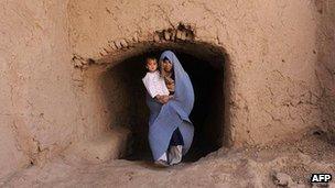 Afghan woman holds her baby as she walks in the outskirts of Herat in October 2011