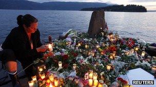 A woman lights a candle to pay her respects to the victims of the shooting spree and bomb attack in Norway, on the shore in front of Utoeya island, northwest of Oslo, 26 July