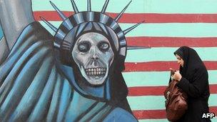 An Iranian woman walks past an anti-US mural painted on the wall of the former US embassy in Tehran on 19 November 2011