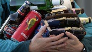 A person holds an armful of assorted alcoholic drinks