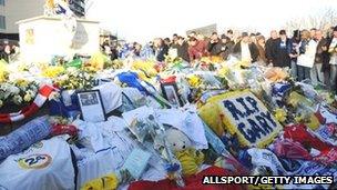 Fans gather as floral tributes are left to Gary Speed at the foot of the Billy Bremner statue outside Leeds United's Elland Road