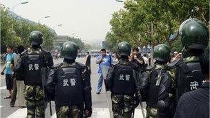 Paramilitary police stand guard as hundreds of people protest in Dalian