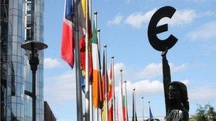 Flags and a statue holding the euro sign