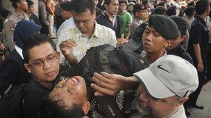 Security personnel evacuate a Indonesian man after he collapsed while queueing for discounted BlackBerry smart phones at a mall in Jakarta