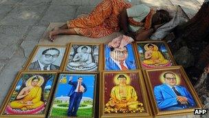 A woman on the pavement selling posters of Ambedkar and the Buddha