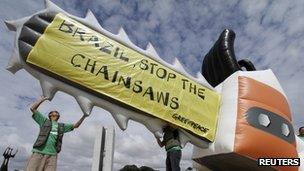 Greenpeace activists holds an inflatable balloon, shaped like a chainsaw to protest the vote on the new Forest Code in Brasilia December 6, 2011