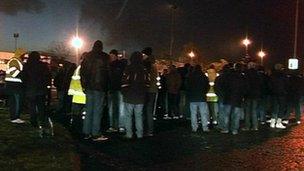 Men standing outside an oil refinery