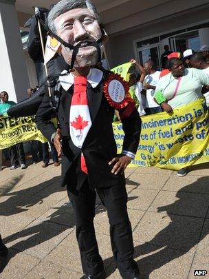 An activist wears a mask depicting the face of Canadian PM Stephen Harper in Durban