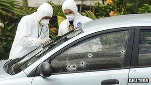 Forensic workers examine the car of Alfredo Landaverde who was shot dead on Wednesday