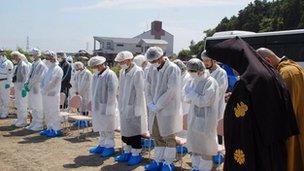 Residents of Tomioka in white protection suits evacuated to the city of Koriyama