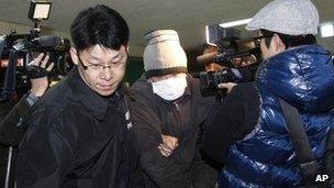 A Chinese fisherman (centre) is led by a South Korean police officer as he arrives at Incheon Coast Guard office in South Korea, 13 December 2011