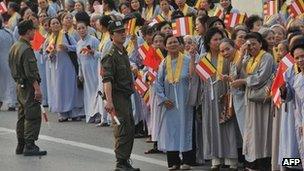 Vietnamese buddhist followers watch as monks exit a Vietnam Airlines aircraft at Hanoi's Noi Bai airport on March 3, 2010