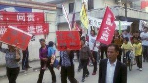 Residents holding placards march on a street during a protest in Wukan village of Lufeng, China's Guangdong province, 22 November 2011