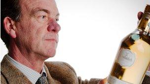 A Bonham's auctioneer inspects the bottle of Glenfiddich whisky