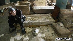 Iraq's National Museum Deputy Director Muhsin Hasan holds his head in his hands as he sits on destroyed artefacts in Baghdad (13 April 2003)