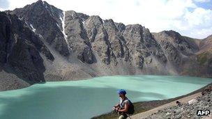 Tourist walks along banks of Lake Ala-Kul, in mountains of Kyrgyzstan