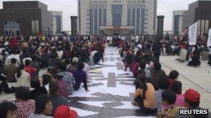 Residents sit next to a banner outside the city government building during a protest in Lufeng on 21 November