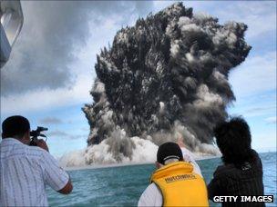 People watch as smoke billows up from an underwater volcano