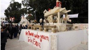 People gather by a statue representing the cart of Mohamed Bouazizi in Sidi Bouzid, 17 December 2011