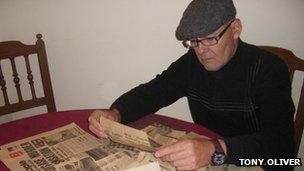 Tony Oliver reads newspaper cuttings about his brother's murder