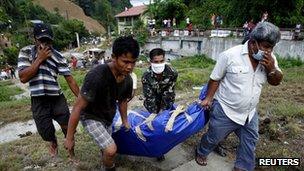 A soldier and local government workers carry a body bag containing the body of a flood victim for burial in Iligan city in southern Philippines