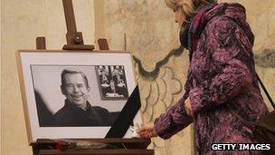 A mourner lays a Christmas angel at a photograph of former Czech President Vaclav Havel