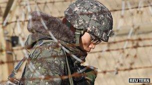 A South Korean soldier walks behind a barbed wire fence near the demilitarised zone on 20 December 2011