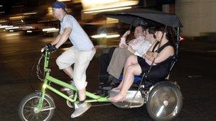 Passengers on a rickshaw in Soho, London