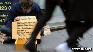 Shoppers walk past a homeless man