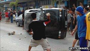 Man throws brick at car