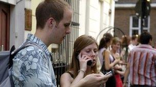 Man texting, woman on mobile