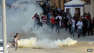 Bahraini anti-government protesters run for cover from tear gas during clashes with riot police near the headquarters of the main Shia opposition group (23 Dec 2011)