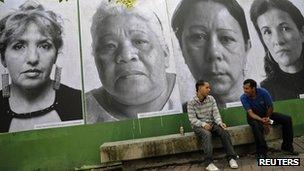 Men sit in front of giant portraits of mothers whose children have been victims of violence in Caracas