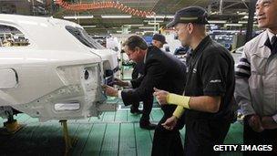 Prime Minister David Cameron installs a badge on a car at a Toyota plant on November 24, 2011, in Burnaston, United Kingdom