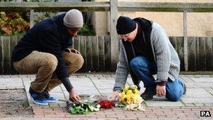 Two men lay flowers on the Stephen Lawrence Memorial in Eltham on 3 January 2011 after the jury's verdict