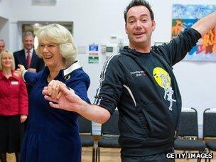 The Duchess of Cornwall, president of the National Osteoporosis Society, and Craig Revel Horwood dance during a visit to a school in 2009.