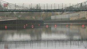 Bright orange buoys stop river traffic from sailing underneath the Victoria Bridge on the River Avon in Bath