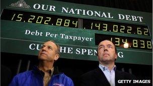 Supporters of Mitt Romney stand behind in front of a debt clock in Exeter, New Hampshire, 8 January 2012