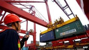 Worker operating hoists to unload containers at the Kaikou port, in south China's Hainan province, 8 January 2012