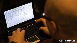 Man at hacker conference looks at lines of computer code on a laptop