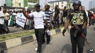 A police officer walk with protesters on fourth day of a nationwide strike in Lagos, Nigeria, 12 January 2012