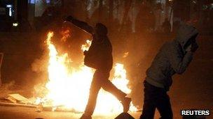 A protester throws stones at police in Bucharest. Photo: 15 January 2012