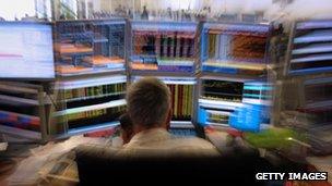 Stock market trader on the phone in front of screens