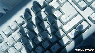 The shadow of a hand covers a computer keyboard