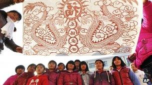 An art teacher, front left, shows pupils' paper-cutting samples depicting dragons at a primary school in Zouping county, China