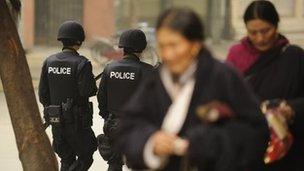 Armed Chinese police (L) patrol on a street as Ethnic Tibetans walk past in Chengdu in southwest China's Sichuan province on January 27, 2012.