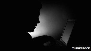 A silhouette of a man using a laptop