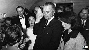 Jacqueline Kennedy (R) watches as US Vice-President Lyndon Johnson (C) is administered the oath of office