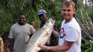 Andy Giles holds fish in Sierra Leone