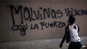 A woman in Buenos Aires finishes graffiti which reads: We will get Malvinas back with the strength of..."